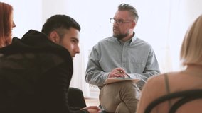 Professional psychotherapist talking with young rebellious people during meeting