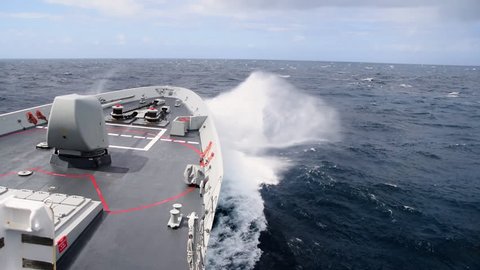 A Navy Destroyer underway through the Atlantic Ocean. View of the bow cutting the waves from the bridge.
