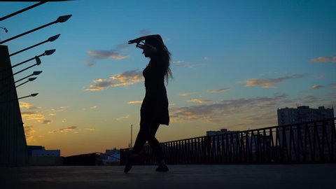 Silhouette of a lovely active girl dancing jazz modern in summer evening.