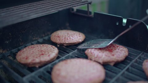 Close up of spatula flipping hamburgers on barbecue
