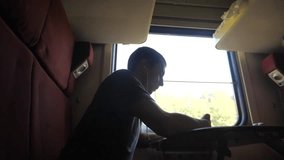 man silhouette travel is sitting on the train carriage holding sits by the window a smartphone Railway and drinking coffee and tea. slow motion video. man writes messages in lifestyle the smartphone