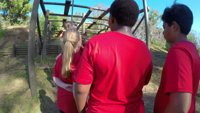 Trainer assisting a school girl in rope climbing during obstacle course on a sunny day  - Powered by Shutterstock - Get 15% off with code: PIKWIZARD15