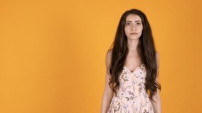 Bored and annoyed beautiful teenager girl looking at camera isolated on orange yellow background