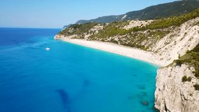 Aerial drone bird's eye view video of popular beach of Milos with turquoise clear waters and sun beds, island of Lefkada, Ionian, Greece