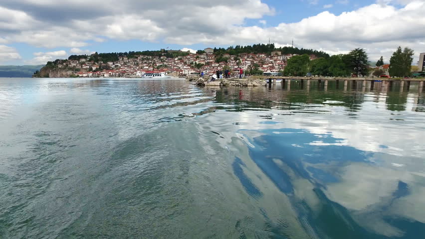 Boat ride pov to Ohrid lake and old town with ruined fortress at hill top
