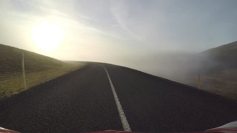 POV Driving down curving mountain roads into valley fog, Iceland, toward sun.mov
