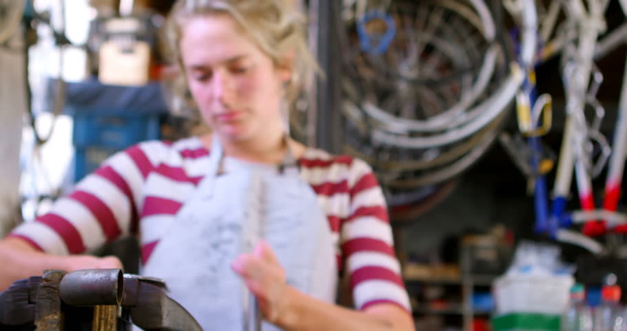 Front view of beautiful Caucasian woman measuring bicycle tool at workshop