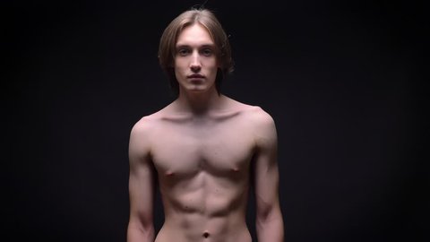 muscular bare young white sportsman looking at the camera with power concentrated on black background