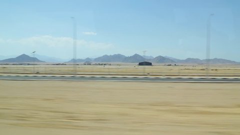 View from window of bus driving along road in Sharm el Sheikh, Egypt. Sandy deserted landscape with horizon, sandy ground, mountains and blue sky. Real time full hd video footage.
