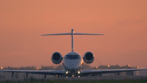 Business jet is taxiing on the taxiway before take off at sunset