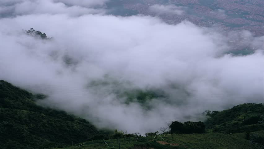 Beautiful timelapse of the city of Medellin from the mountains with clouds and fog rolling off the hills