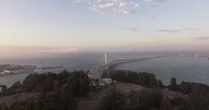 Aerial footage from Treasure Island in San Francisco, flying over the water towards the San Francisco-Oakland Bay Bridge and the Oakland skyline.