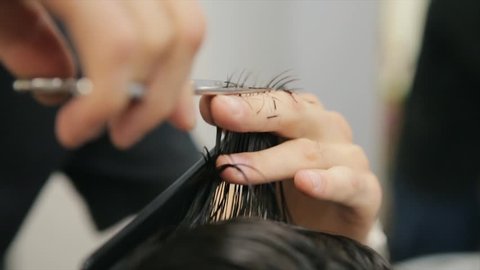Barber Cuts the Hair in the Barbershop. Man hairdressing with scissors cuts the Hair. Slow Motion. Close Up