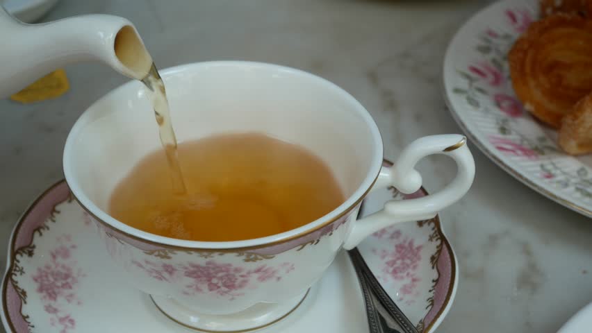Pouring english tea into the beautiful english tea cup with background of sweet dessert (scone) Royalty-Free Stock Footage #1016659375