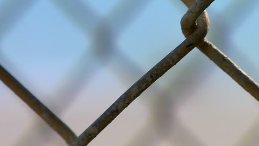 rack focus through a couple layers of chain link fence to a scenic shot of a
