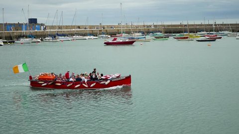 Dublin, Co.Dublin / Ireland - 08 05 2018: Howth, Ireland, August 2018 - Daytrippers arrive back in the harbor in a red boat.
