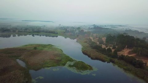 aerial view of village by the lake in the morning mist, aerial view of lake at sunrise, fog and sun over rivers, aerial view of fog over the marsh at dawn