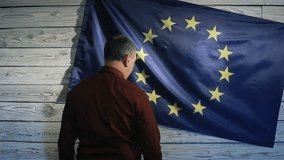 politician scared standing near the flag of the European Union