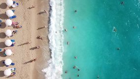Aerial top view video of tropical sandy exotic emerald paradise sandy crowded beach with sun beds and umbrellas
