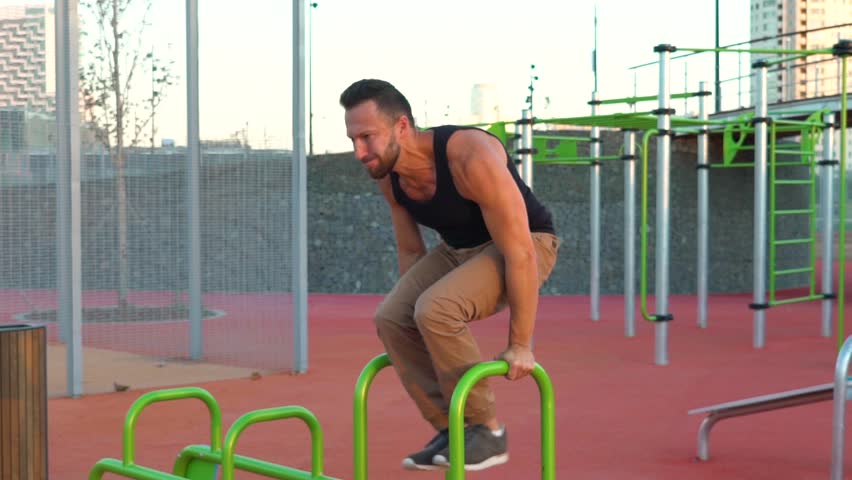 Young man doing sports exercises on a sports field in slow motion