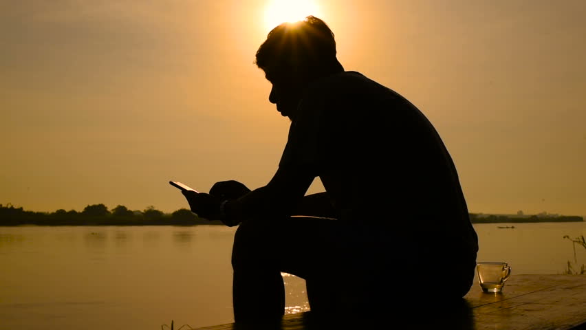 Silhouette of Man sitting near the river