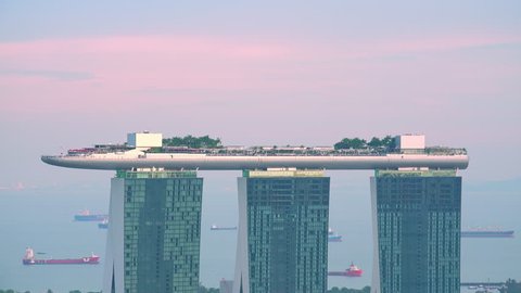 SINGAPORE - OCT 19, 2017: Amazing view of Marina Bay Sands hotel with swimming pool and restaurant on roof. Sunset zooming out panorama of beautiful resort in central district of modern Asian city