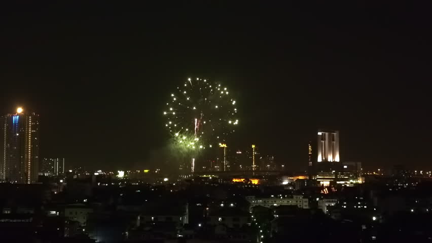 Spectacular view of colorful fireworks exploding in night sky over Bangkok. Astonishing cityscape with modern city against eye-catching pyrotechnic show on background. Holiday celebration or festival.