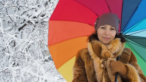 Girl in a snow park with a colored umbrella.