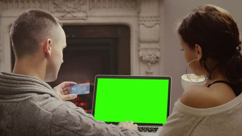 Newly wedded couple making purchases on internet using credit card. Back view of young two people shopping online together. Green screen.
