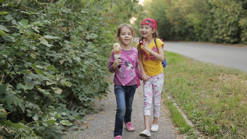 Two little girls girlfriend go home on the side of the road and talk