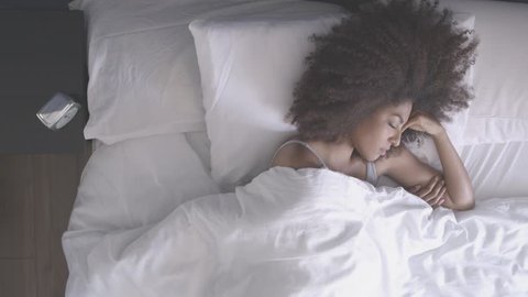 African American woman sleeping at home and waking to an alarm