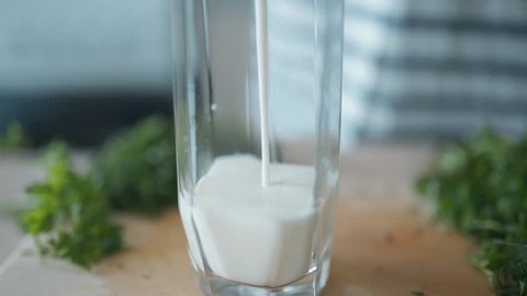 Pouring white drink - milk, drinking yogurt, kefir, shake - into glass.