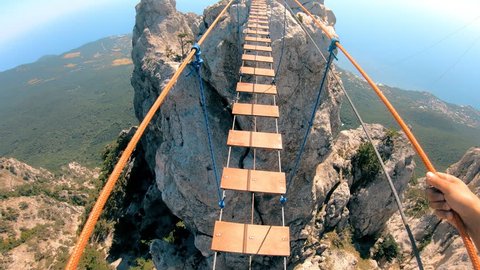 The rope bridge. Crossing over a suspension bridge in the mountains. Extreme sport. GoPro.