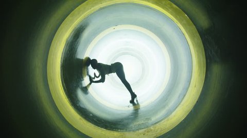 A silhouette of beautiful sexy girl , woman dancing inside circle tube . Against colored & gray background . Real decoration . None computer graphics . Shot on Arri Alexa Cinema Camera in 4K .
