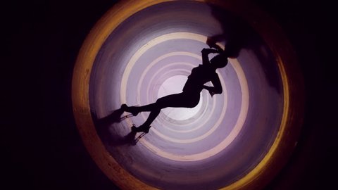 A silhouette of beautiful sexy girl , woman dancing inside circle tube . Against colored & gray background . Real decoration . None computer graphics . Shot on Arri Alexa Cinema Camera in 4K .

