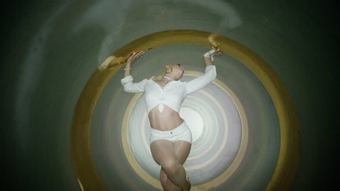 A beautiful blonde and sexy girl , woman dancing inside circle tube . Against yellow gold & gray background . Real decoration . None computer graphics . Shot on Arri Alexa Cinema Camera in 4K .