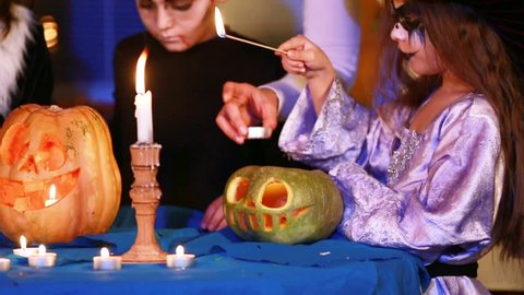 Girl lights a candle in a monster pumpkin
