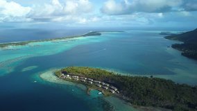 Aerial footage from a drone of luxury overwater villas with palm trees, blue lagoon, white sandy beach at Bora Bora island, Tahiti, French Polynesia, South Pacific Ocean (Bora Bora Aerial)
