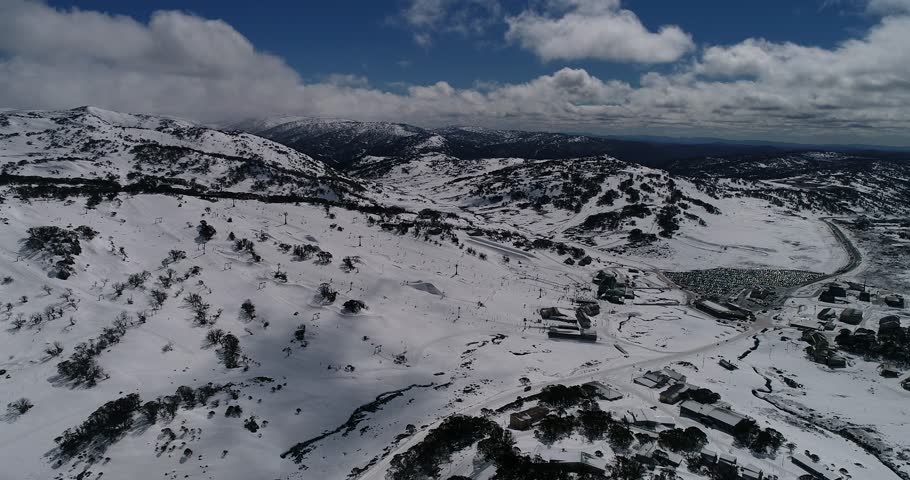 Panning over Perisher valley town popular ski resort in Australian Snowy Mountains in winter over snow covered ranges and chair lifts.
