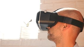 Man using virtual reality headset at office. Bearded man uses VR headset display for game ore for work