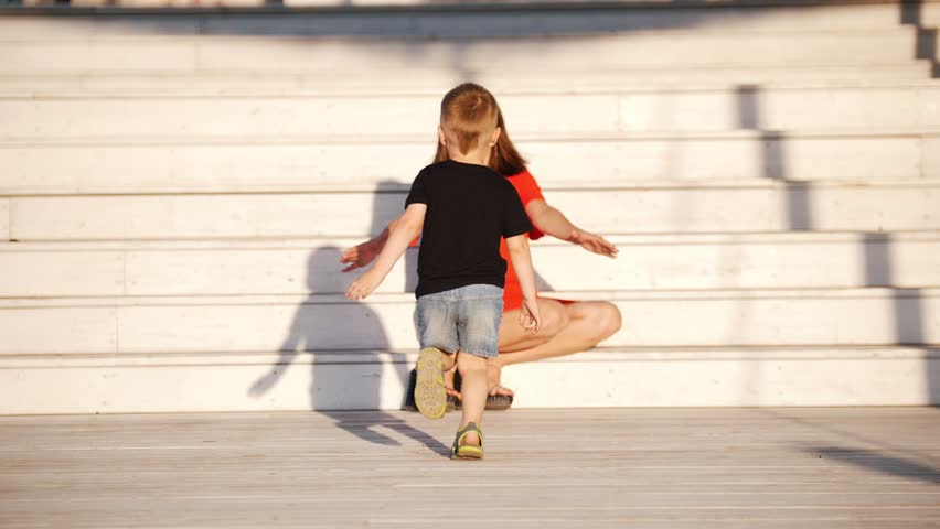 A little boy runs to his mother, a woman raises a child in his arms. Happiness, love.