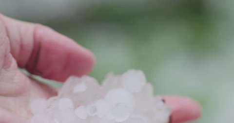 Slow motion closeup pov male hand holding hailstones after hailstorm