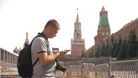 Travel and technology. Happy tourist man looks the navigator smartphone taking selfie with backpack. slow motion video. on lifestyle Red Square in Moscow, Russia Kremlin. tourist journey travel man in