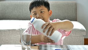 Cute little boy asian. He is pouring milk into glass. video 4k Slow motion