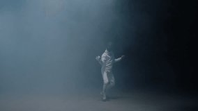 Professional fencer in protective uniform practicing maneuvers with sword alone in dark studio . Fencing demonstration on black smoked background . Shot on Arri Alexa cinema camera in slow motion .