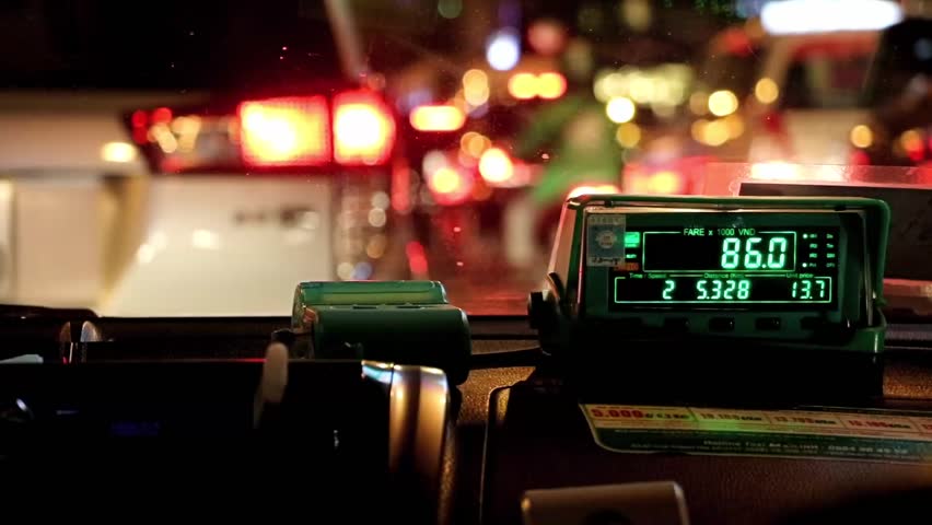 Waiting in night city traffic inside taxi car. The digital taxi meter on the dashboard of cab shows kilometer and cost.   Royalty-Free Stock Footage #1016753914