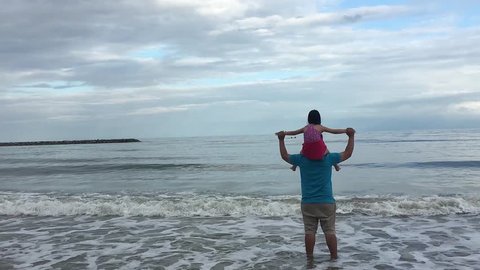 father's day. child daughter sits on her  fat dad shoulders outdoors on a summer beach.  family conception. Asian girl playing with her father, playing the sea on vacation
