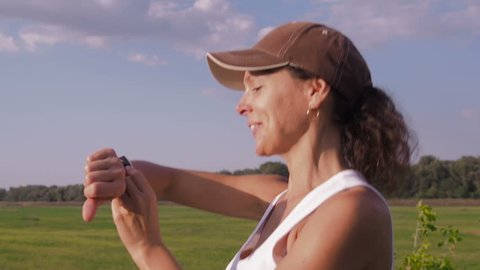 A woman in nature is engaged in fitness with a sports gadget.