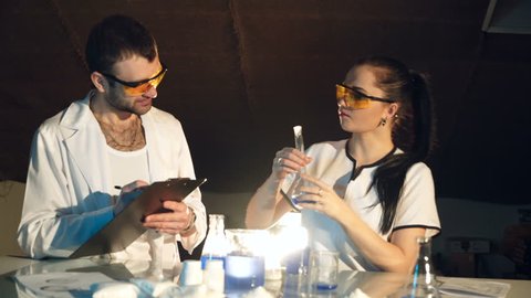 Experiments in the laboratory of chemistry. Chemists examine the flask with liquid. Concept of science