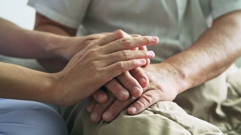 Comforting hand. Young nurse holding old man's hand. Senior care, care taker and senior retirement home service concept. Close up shot.